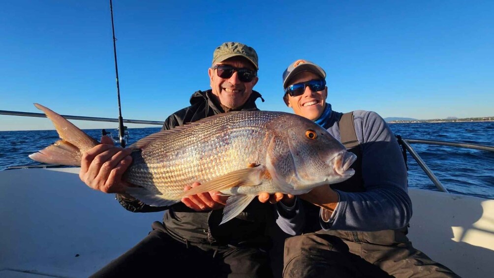 Two people on a boat holding a large fish. 3