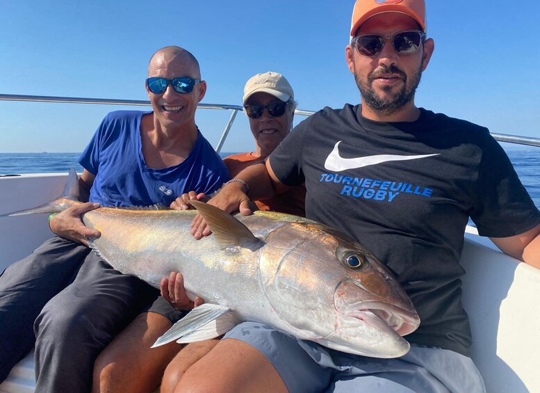 Three people on a boat holding a large fish. 1