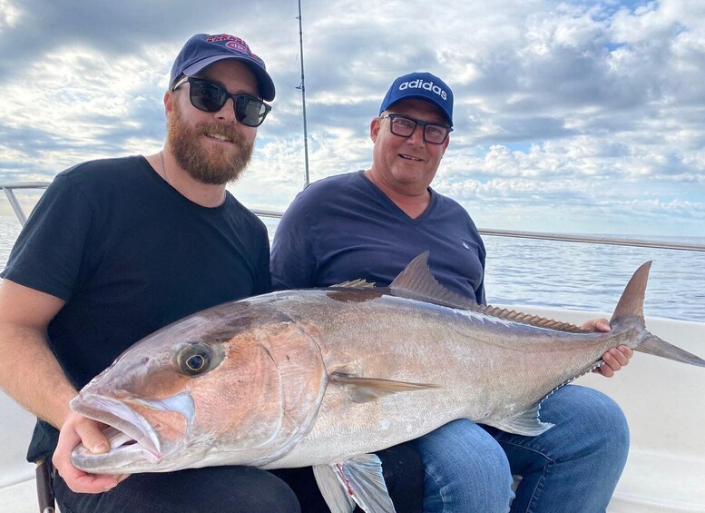 Two people on a boat holding a large fish. 4