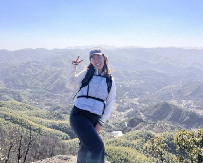 A person standing on a mountain ridge with a vast mountainous landscape in the background. 3
