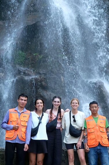 A group of people standing in front of a waterfall. 2