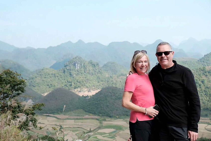 Two people standing with a mountainous landscape in the background. 4