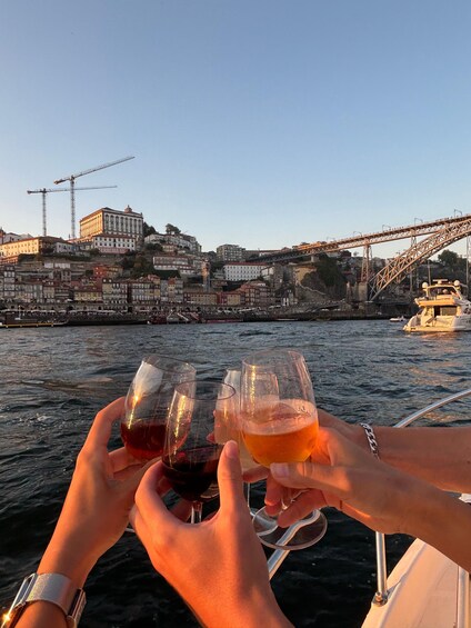 Two hands holding wine glasses, a bridge, and buildings in the background. 2