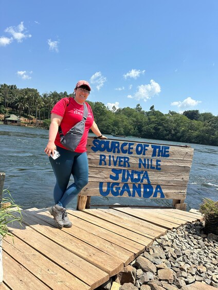 A person standing on a wooden dock with a sign that reads 'Source of the River Nile Jinja Uganda.' 2