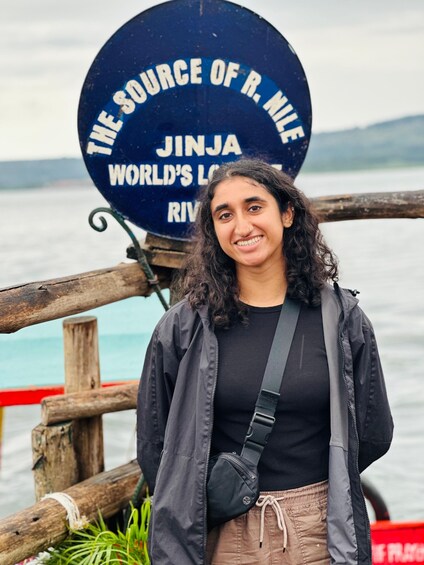 A person standing in front of a sign that reads 'The Source of R. Nile Jinja World's Largest River.' 4