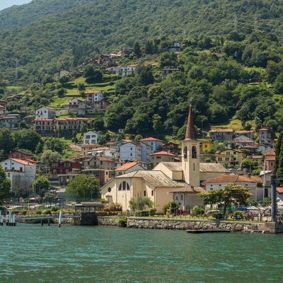 A coastal town with a prominent church steeple, surrounded by lush greenery and residential buildings. 1