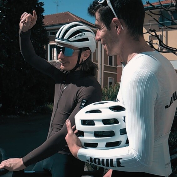 A person holding a white helmet with ventilation holes, wearing a dark long-sleeve top, and a white helmet with 'MET' on it. 5