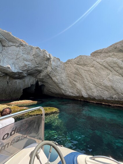 A boat near a rocky cave entrance with clear water. 4