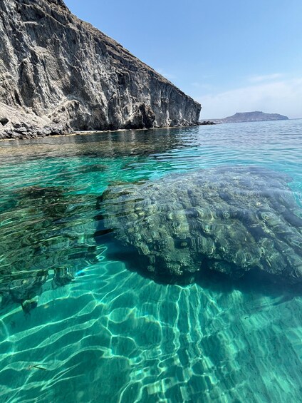Clear turquoise water, rocky formations, and a distant island. 3