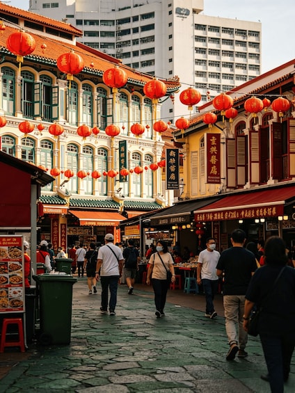 A street market with traditional buildings, red lanterns, and people walking. 3