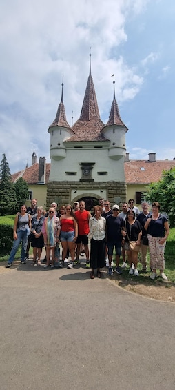 Un groupe de personnes se tient devant un château doté de deux hautes tours et d’une horloge. 4