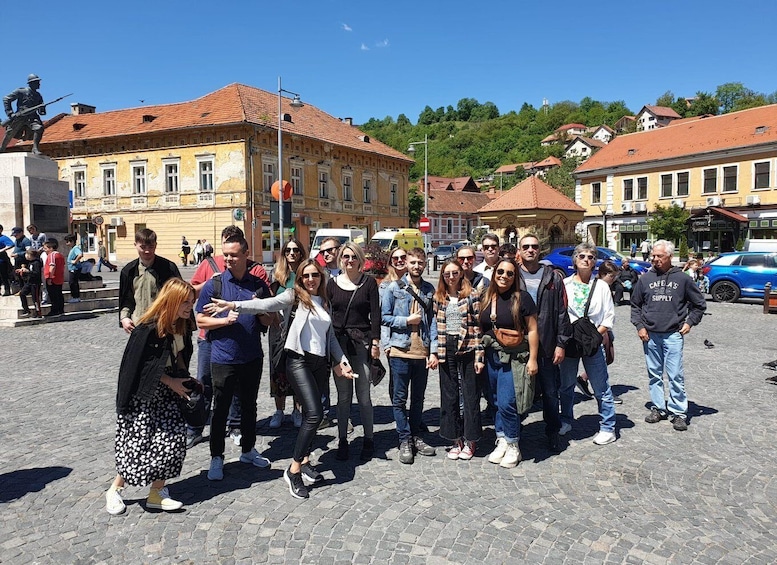 Un groupe de personnes posant sur une place pavée, avec des bâtiments historiques et une statue en arrière-plan. 5