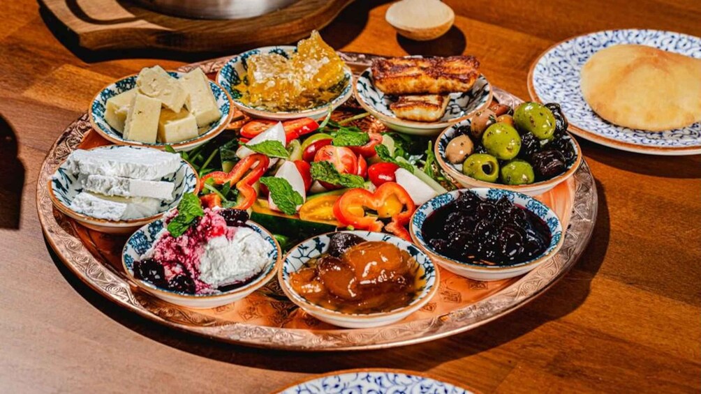 A variety of food items on a tray, including cheese, olives, and a salad. 3