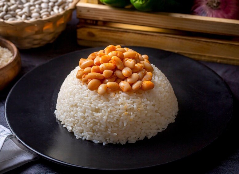 A mound of white rice topped with orange beans on a black plate. 1
