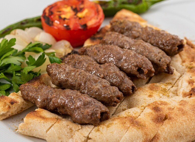 Grilled kebabs, flatbread, grilled tomato, and parsley on a plate. 4