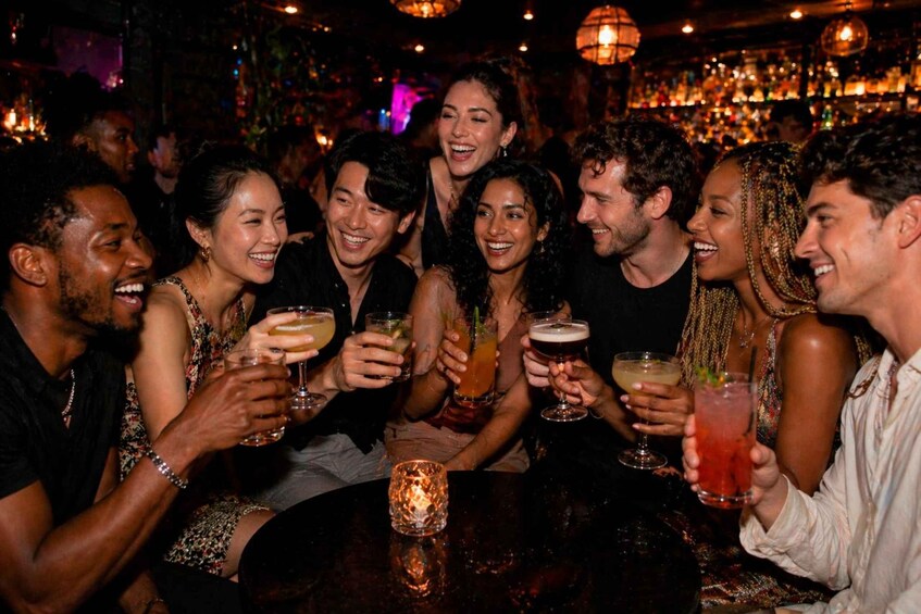 A group of people toasting with drinks at a bar. 3