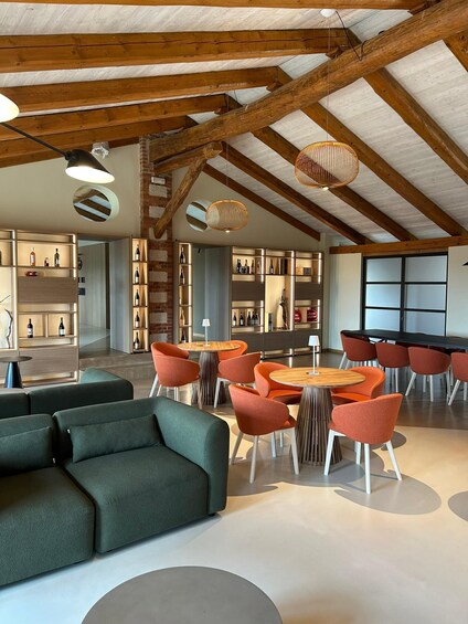 A modern interior with exposed wooden beams, a green sofa, orange chairs, and a wine rack. 2