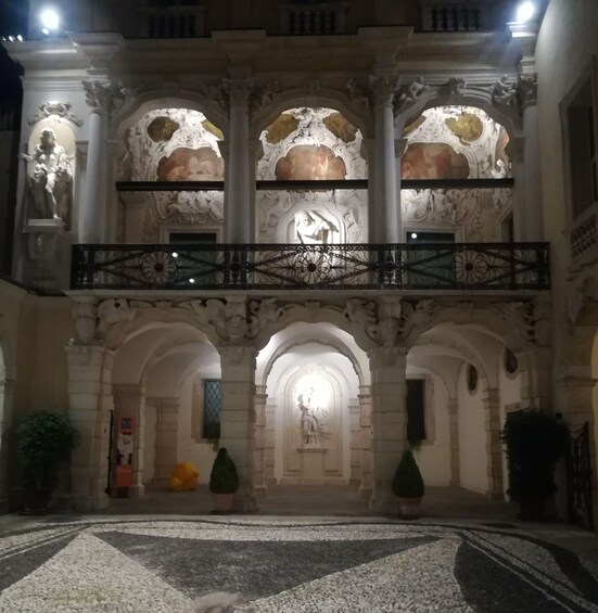 An ornate building with a central statue, arched doorways, and a decorative balcony. 2