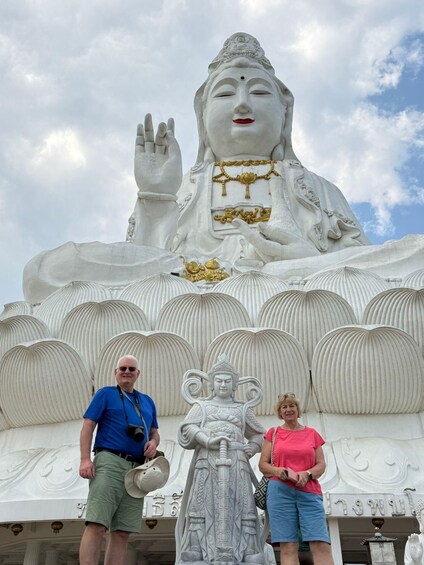 A large white statue of a seated figure with a raised hand, surrounded by intricate carvings and smaller statues. 2