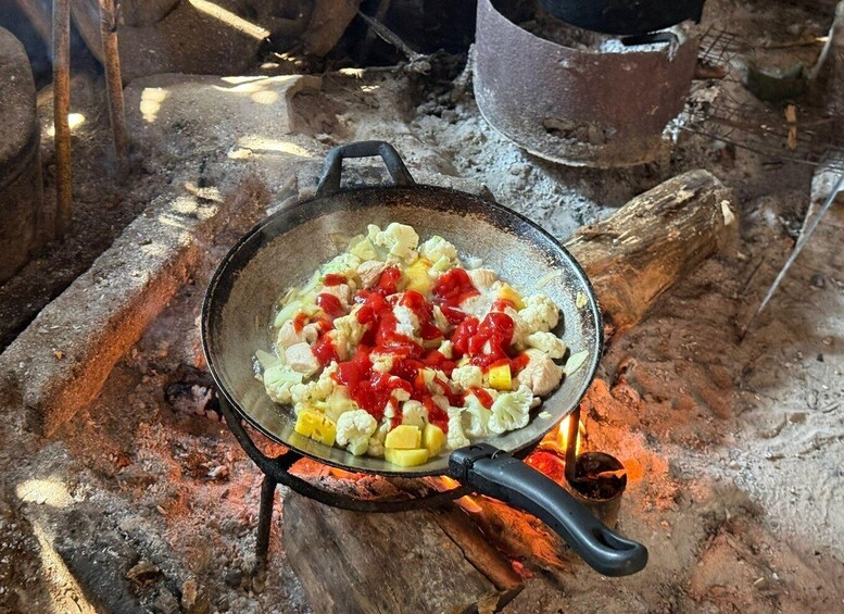 A pan on an open fire with chopped vegetables and sauce. 5