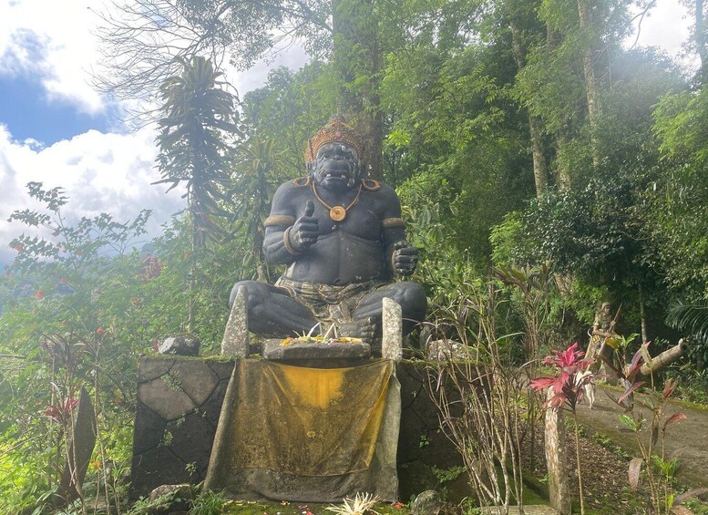 A large seated statue surrounded by lush greenery and a stone structure. 3
