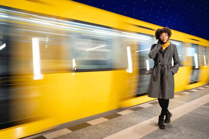 A person standing on a train platform with a moving train in the background. 5