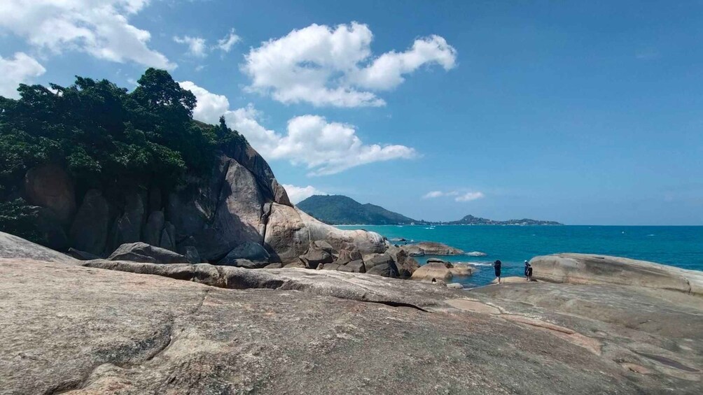 A rocky coastline with large boulders and a clear blue sea. 2