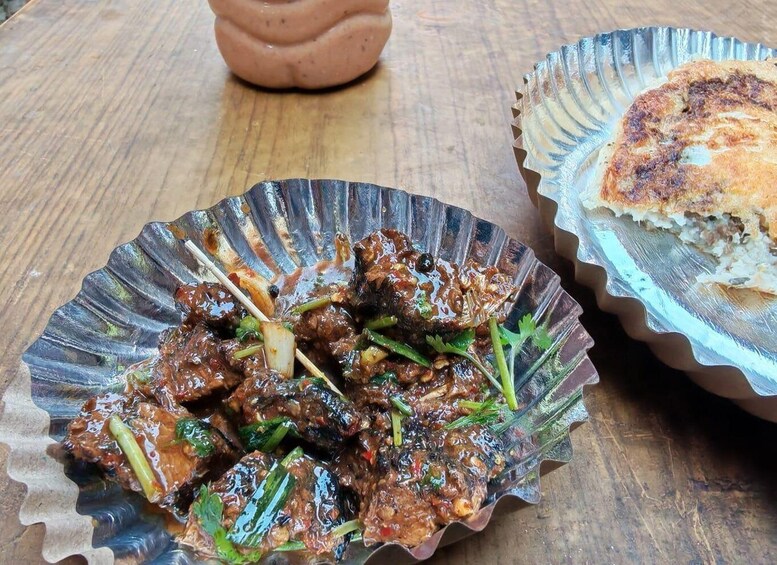 Skewered meat with vegetables on a metal plate, and a piece of flatbread on a paper plate. 4