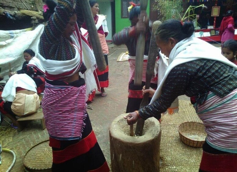 Women engaged in traditional food preparation, using large wooden mortars and pestles. 2