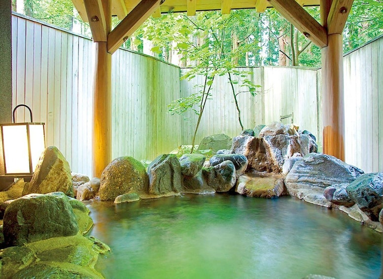 A hot spring bath surrounded by rocks and wooden beams. 2