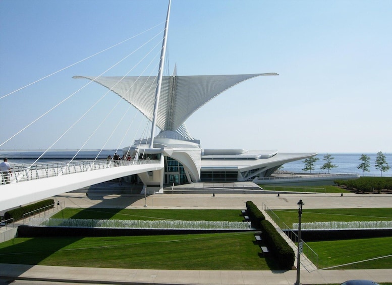 A modern bridge with a distinctive sail-like structure, a pedestrian walkway, and a landscaped area with a fountain. 3