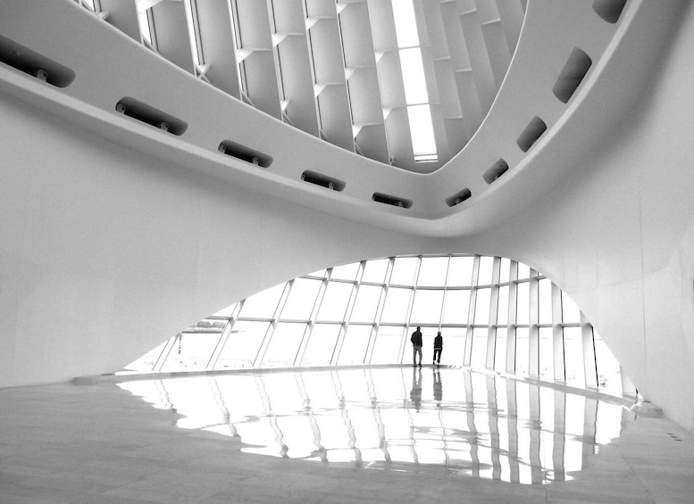 A modern architectural interior with a reflective floor and a large skylight. 2