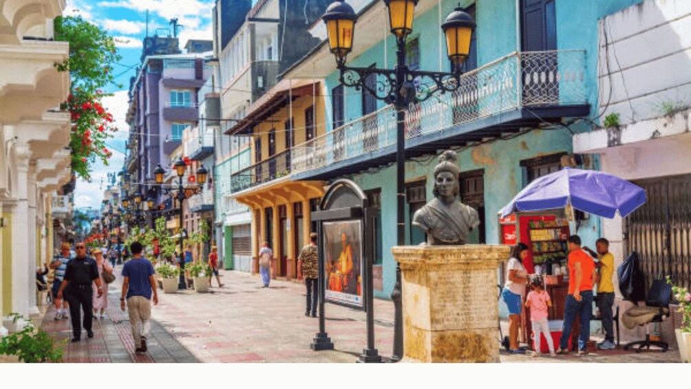 A bustling street with pedestrians, a statue, and traditional buildings. 5