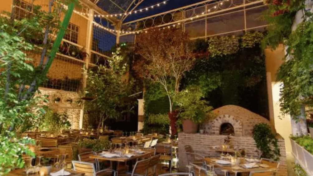 An outdoor dining area with tables and chairs, a brick oven, and string lights. 4