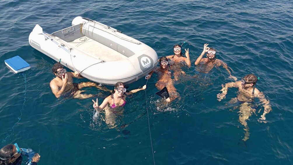 A group of people snorkeling in the ocean, with a small inflatable boat nearby. 2