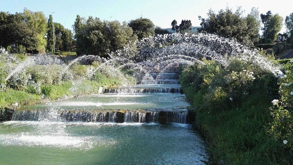 A cascading water feature with multiple tiers, surrounded by lush greenery and trees. 2