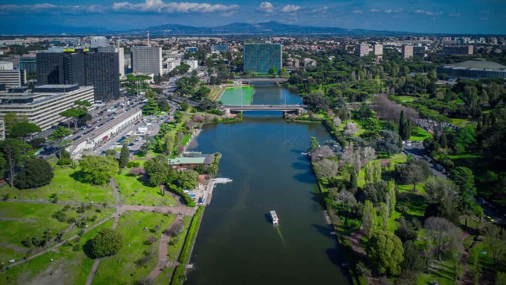 A river with a bridge, surrounded by greenery and urban buildings. 1