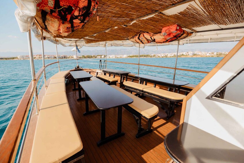 A boat deck with tables and benches, a thatched roof, and a view of a coastline. 2