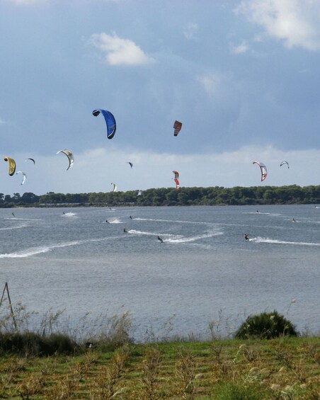 A lake with multiple kitesurfers and windsurfers. 4
