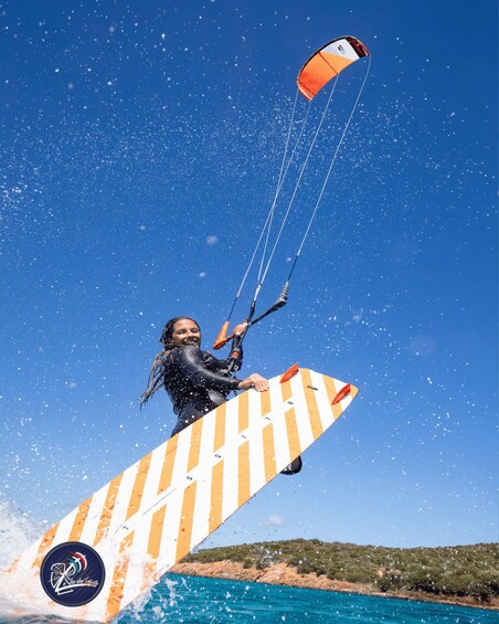A person kite surfing with a striped board and a parachute. 3