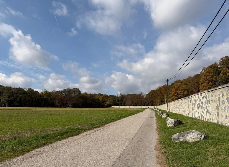 A gravel path alongside a stone wall with trees in the background. 3
