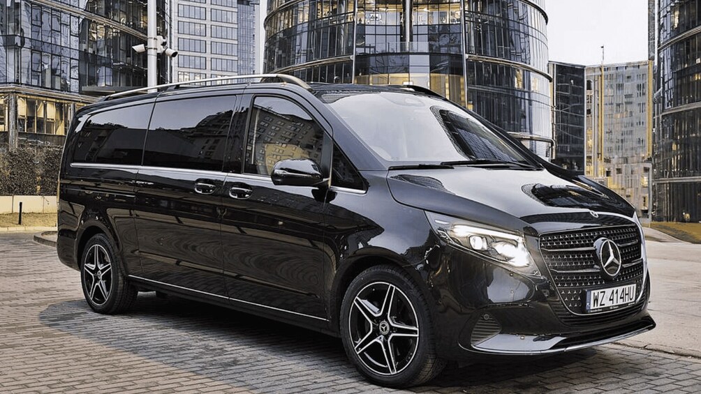 Musta Mercedes-Benz Sprinter -pakettiauto oli pysäköitynä modernien lasisten rakennusten eteen. 3