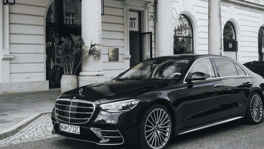 Musta Mercedes-Benz -auto oli pysäköitynä rakennuksen eteen. Rakennuksessa oli klassinen arkkitehtuuri, johon kuului muun muassa pylväitä ja kaarikkunaikkunoita. 1
