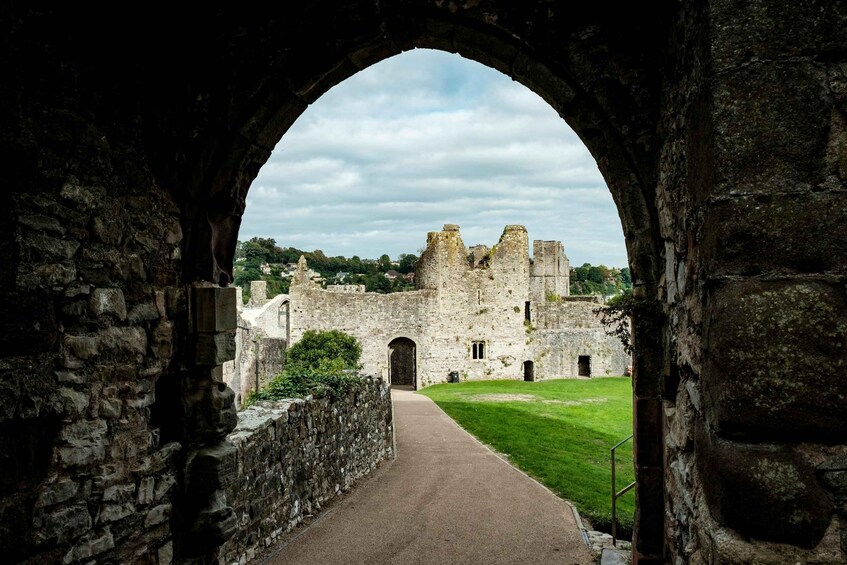 An arched stone gateway leading to a historic castle with a grassy courtyard. 4