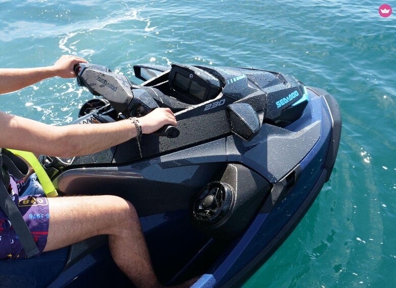 A person riding a black Sea-Doo 230 jet ski on clear blue water. 5
