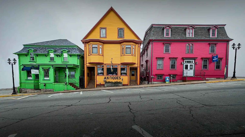 Three colorful buildings: a green building with a 'SALE' sign, a yellow building with 'ANTIQUE' signage, and a pink building with a 'VISA' sign. 2