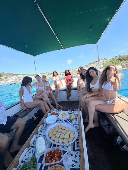 A group of people on a boat with a table of snacks and drinks. 2