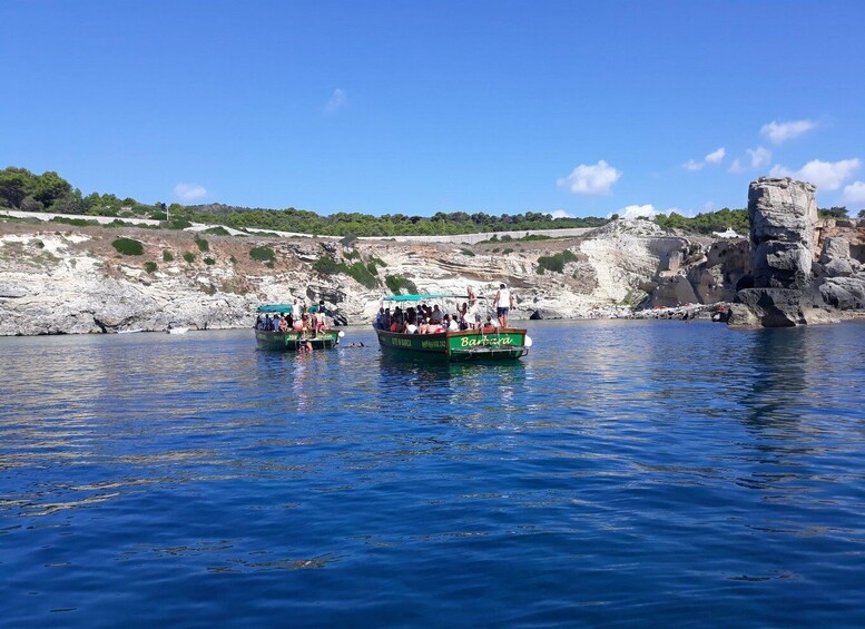 Two boats on a calm sea with rocky cliffs in the background. 3