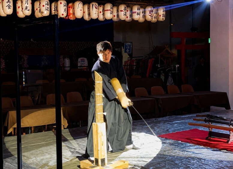 A person performing a martial arts demonstration with a wooden staff in a dimly lit indoor setting. 4