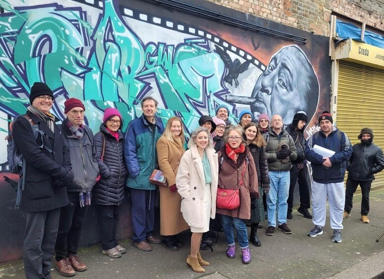 A group of people standing in front of a mural with abstract designs and a film strip. 1